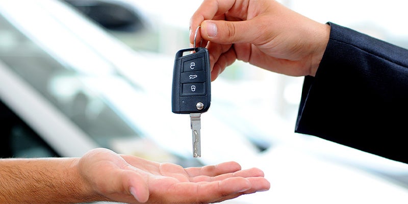 Car salesman passing key